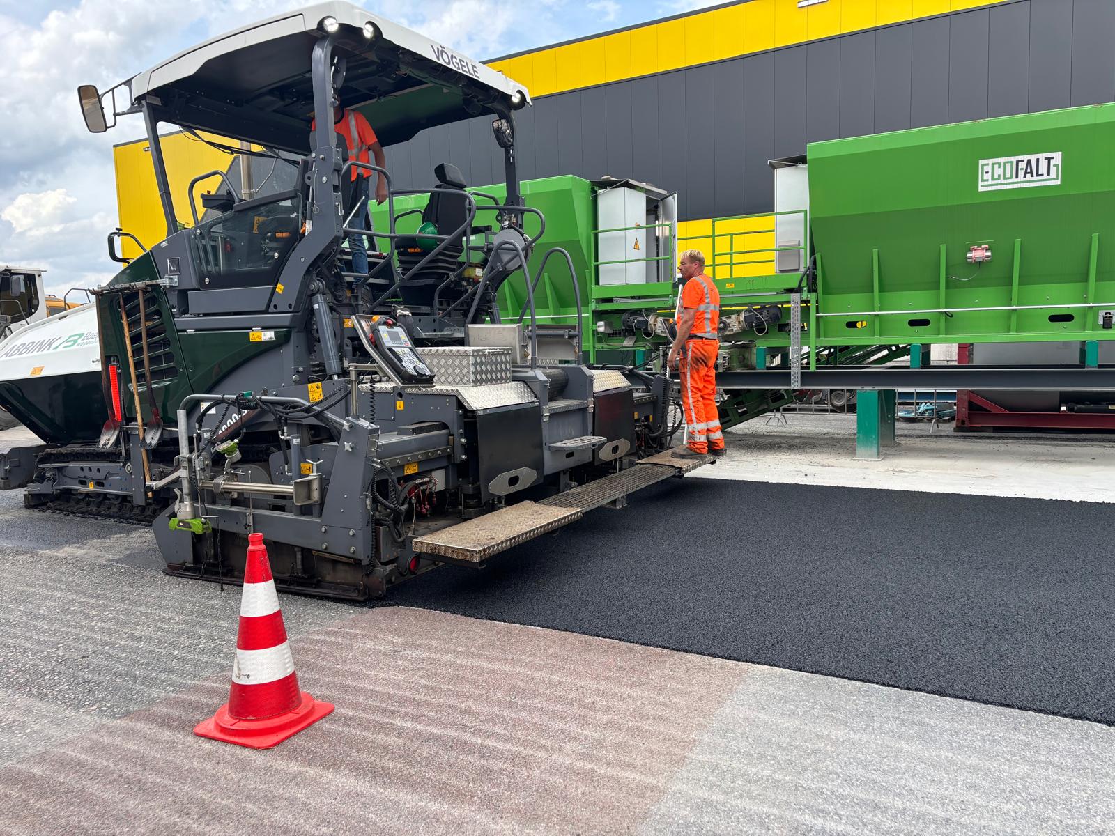 Asfalteermachine brengt het product ecofalt aan op een proefvak.