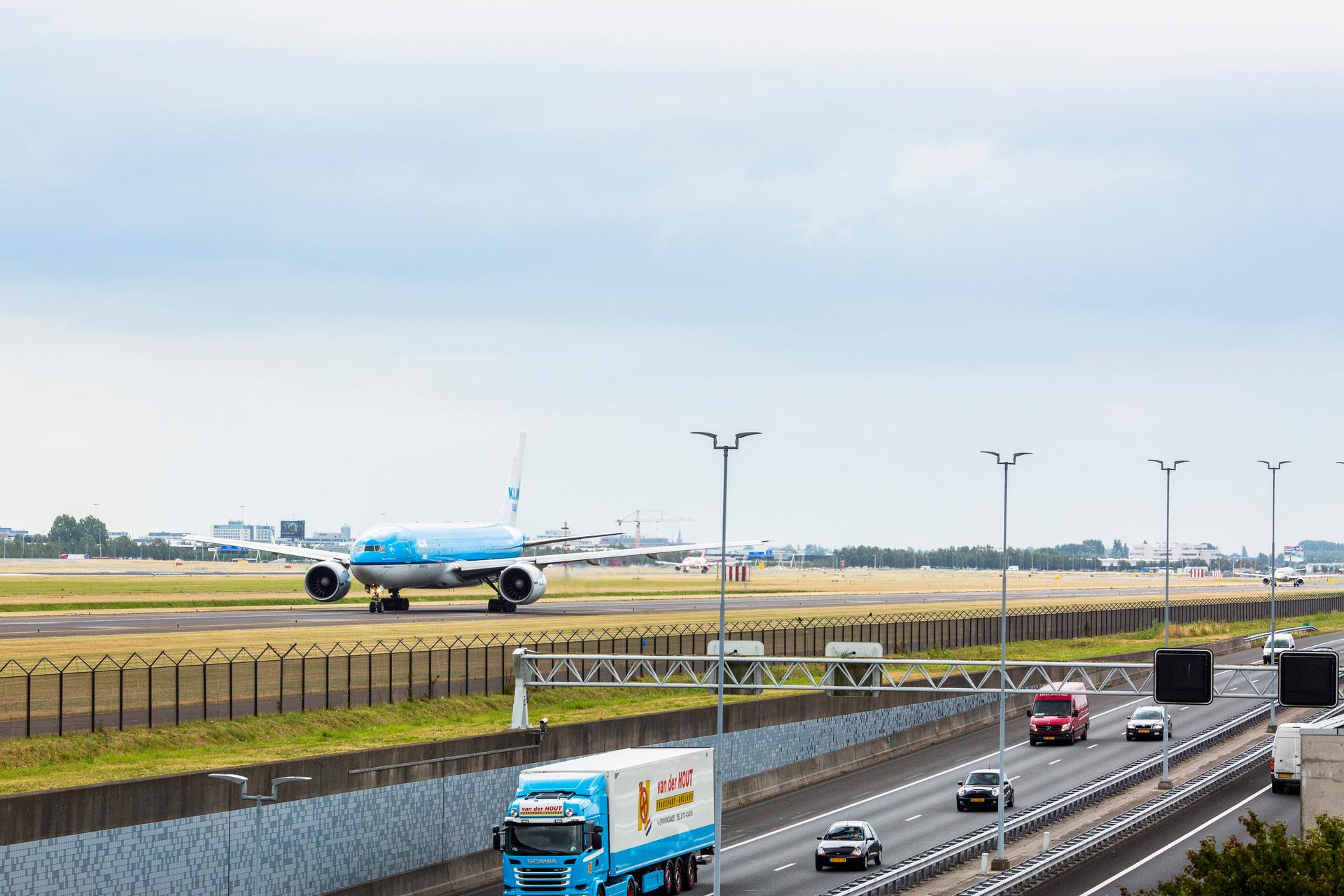 Een vliegtuig landt op de landingsbaan naast de rijksweg.