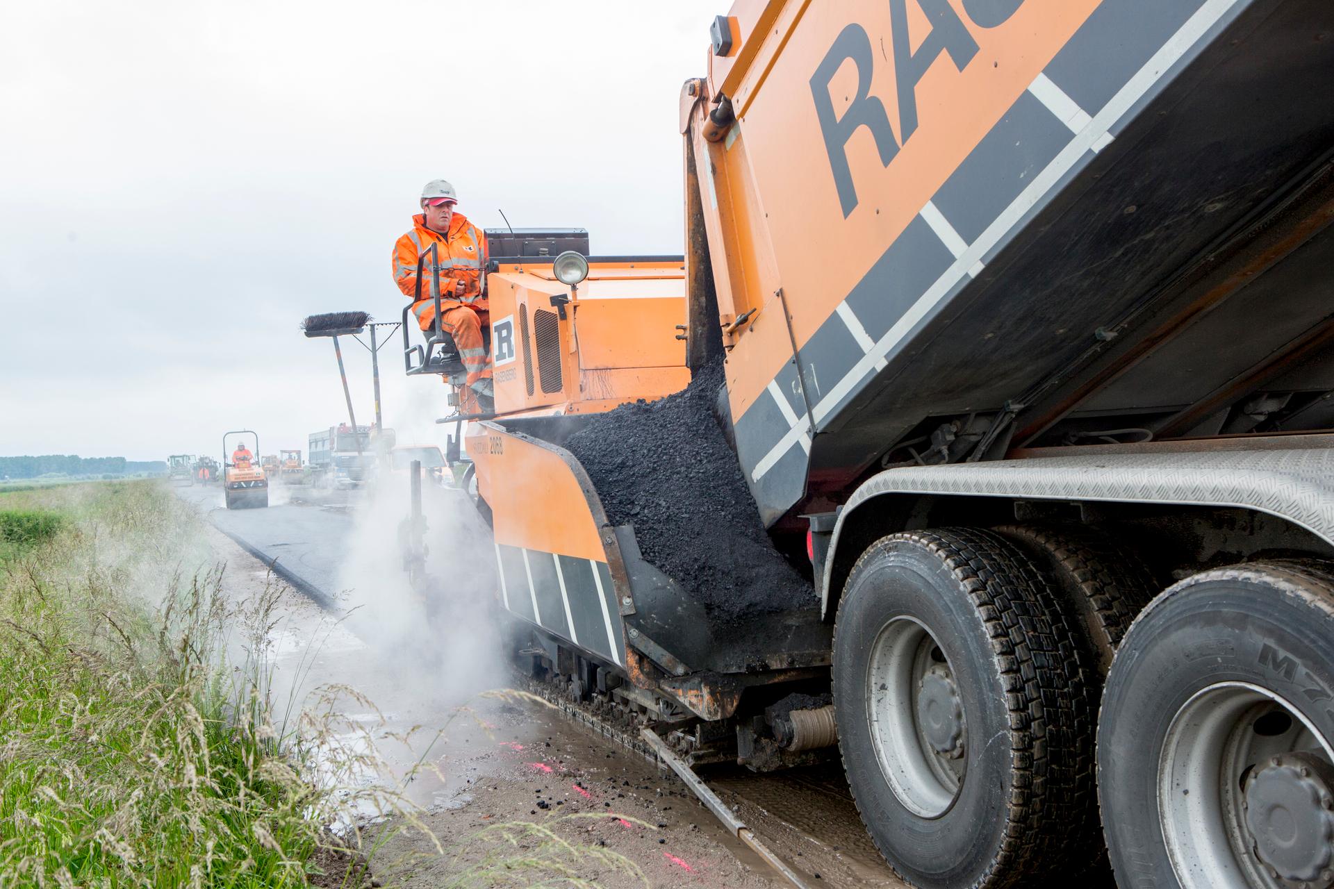 Man op asfalteermachine aan het asfalteren
