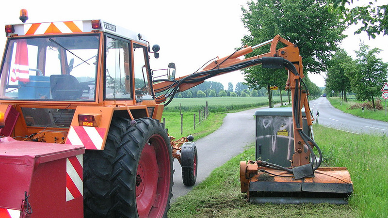 Een tractor die de berm maait